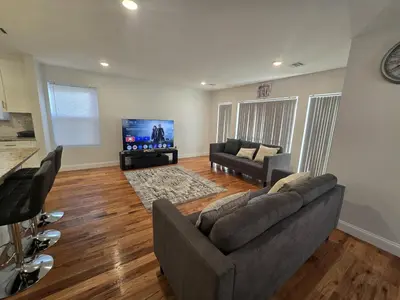a living room with a couch and a flat screen tv at Stylish 3BR Retreat Near EWR Airport NYC Hub in Newark