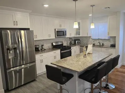 a kitchen with a stainless steel refrigerator and a counter at Stylish 3BR Retreat Near EWR Airport NYC Hub in Newark