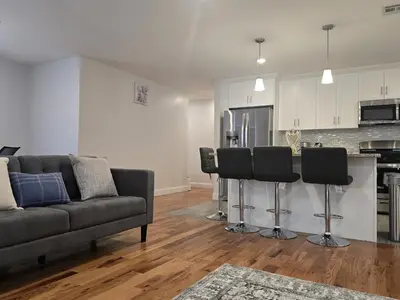 a living room with a couch and a kitchen at Stylish 3BR Retreat Near EWR Airport NYC Hub in Newark