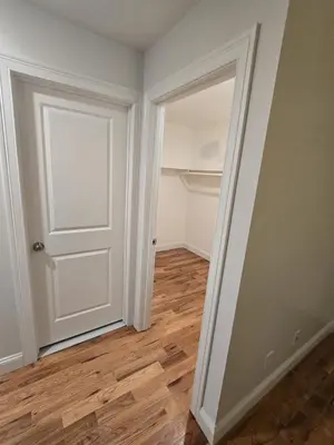 an empty room with a white door and wooden floors at Stylish 3BR Retreat Near EWR Airport NYC Hub in Newark