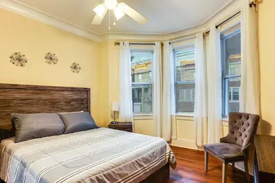 a bedroom with a bed and a chair and windows at Easy NYC Access! Gateway Region Apartment with Yard in West New York