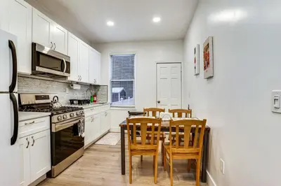 a kitchen with white cabinets and a table and chairs at Easy NYC Access! Gateway Region Apartment with Yard in West New York