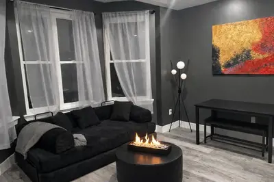 a living room with a couch and a table with a fireplace at Midnight Ember Moody City 1BR Escape in Philadelphia