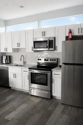 a kitchen with stainless steel appliances and white cabinets at Midnight Ember Moody City 1BR Escape in Philadelphia