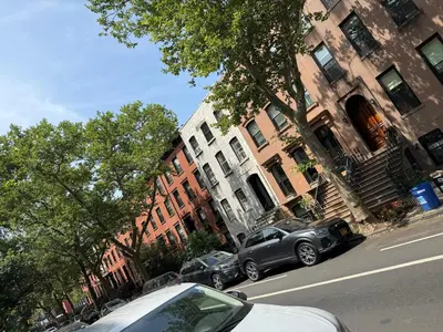 two cars parked in front of buildings on a street at Serene Studio in Brooklyn Heights in Brooklyn