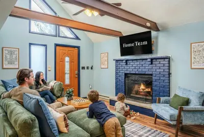 a family sitting in a living room with a fireplace at Movie Theater Game Room Resort Amenity Access in Tobyhanna