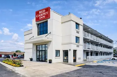 a large white building with a red sign on it at Red Carpet Inn And Suites in Maple Shade