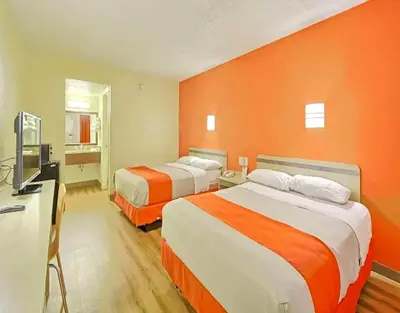 two beds in a hotel room with orange walls at Red Carpet Inn And Suites in Maple Shade