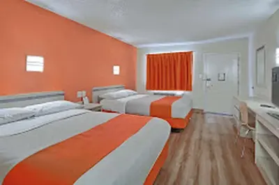 a room with three beds and an orange wall at Red Carpet Inn And Suites in Maple Shade