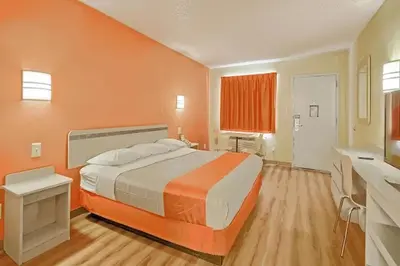 a bedroom with a large bed with an orange wall at Value Extended Stay in Maple Shade