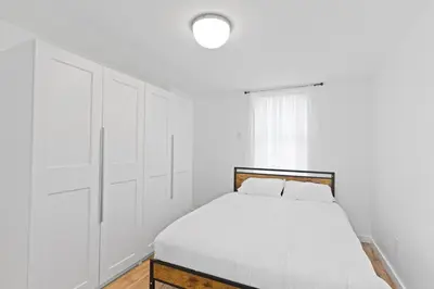 a white bedroom with a bed and a window at New home, 17 min to NYC, 5 min to MetLife Stadium in Carlstadt