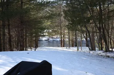 a snow covered field with trees and a body of water at The Vault - Hidden Playroom For Couples - Private Hot Tub - Mountain Views - Riverfront in Barryville