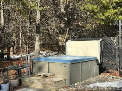 a hot tub with a blue top next to a bench at The Vault - Hidden Playroom For Couples - Private Hot Tub - Mountain Views - Riverfront in Barryville