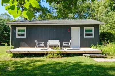 a tiny house with two chairs and a porch at Gilded Cage Escapes - Hidden Playroom For Couples - Private Hot Tub - Mountain Views - Riverfront in Lackawaxen