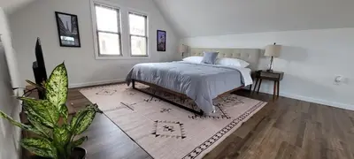 a white bedroom with a bed and a rug at Duplex 15 mins from Time Square! in West New York