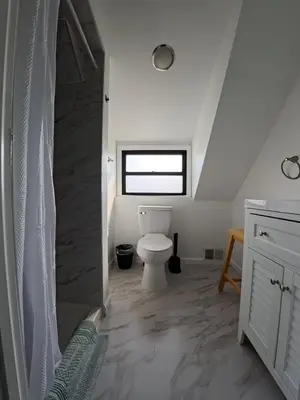 a bathroom with a toilet and a window at Duplex 15 mins from Time Square! in West New York