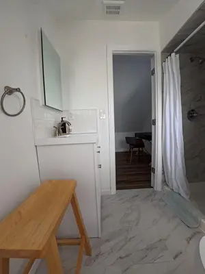 a white kitchen with a sink and a table at Duplex 15 mins from Time Square! in West New York