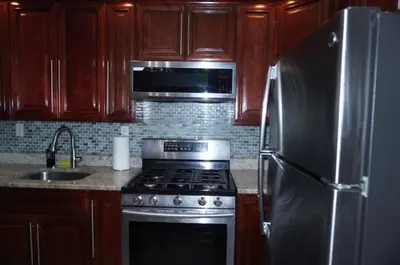 a kitchen with a stove and a stainless steel refrigerator at New York private room 31 in West New York
