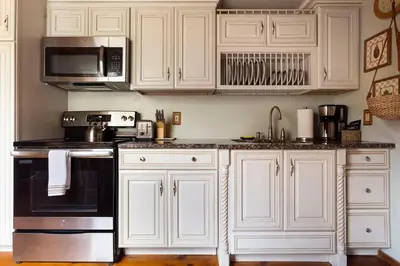 a kitchen with white cabinets and a black appliance at Catskills Aframe, Water View, Goat Sanctuary in Napanoch