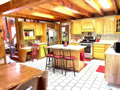 a kitchen with yellow cabinets and bar stools at Log Cabin at the Goat Sanctuary in Napanoch