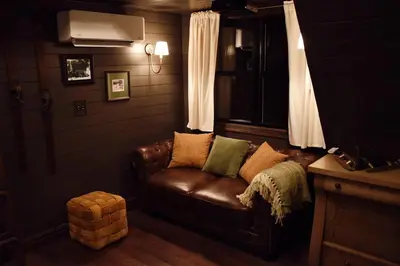 a living room with a brown leather couch and a window at Romantic AFrame Cabin with Firepit, BBQ in Pocono Pines