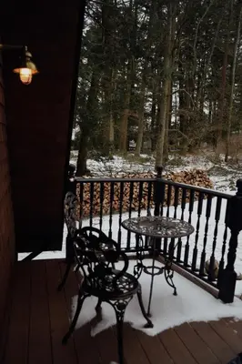 a table and chairs on a porch in the snow at Romantic AFrame Cabin with Firepit, BBQ in Pocono Pines