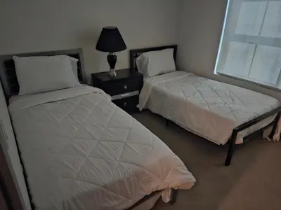 a bedroom with two beds and a lamp and a window at express housing in Philadelphia