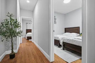 a white bedroom with a bed and a potted plant at Sleeps 19 • 15ft Celings • Near NYC in Jersey City