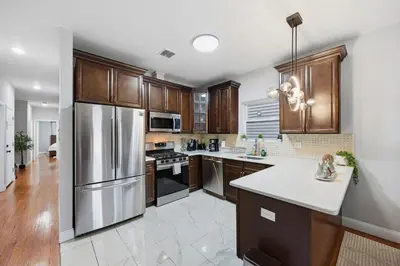 a kitchen with wooden cabinets and a stainless steel refrigerator at Sleeps 19 • 15ft Celings • Near NYC in Jersey City
