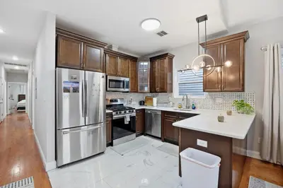 a kitchen with wooden cabinets and stainless steel appliances at Sleeps 19 • 15ft Celings • Near NYC in Jersey City