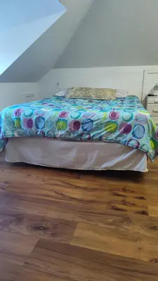 a bed with a colorful comforter sitting on a wooden floor at Oakland House Apartments in Phoenixville