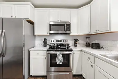 a kitchen with white cabinets and stainless steel appliances at Urban Haven XL - NYC & Newark with free parking in Newark