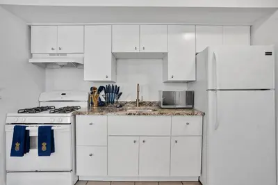 a white kitchen with white cabinets and a white refrigerator at Renovated 2BR in Germantown in Philadelphia