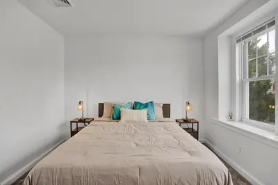 a white bedroom with a large bed and two windows at Renovated 2BR in Germantown in Philadelphia