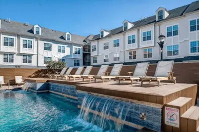 a row of chairs sitting on a deck next to a pool at Landing Amazing 1BD Gym Game Room in Bayonne
