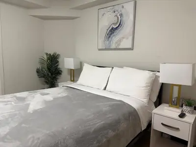 a white bedroom with a bed and two lamps at New York Central Park Suites in New York