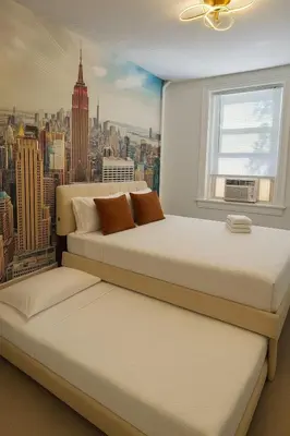 two beds in a bedroom with a view of a city at Renovated 3BR - Near Times Square - Family Groups in West New York