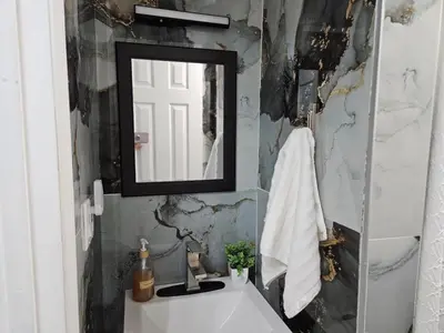 a bathroom with a mirror and a white sink at Renovated 3BR - Near Times Square - Family Groups in West New York