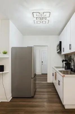 a kitchen with a stainless steel refrigerator and white cabinets at Renovated 3BR - Near Times Square - Family Groups in West New York