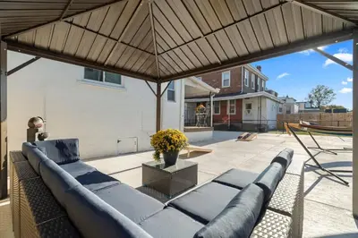 a couch under a large umbrella on a patio at Oasis Spacious-Private Parking 16 Beds 29 Guests in Philadelphia