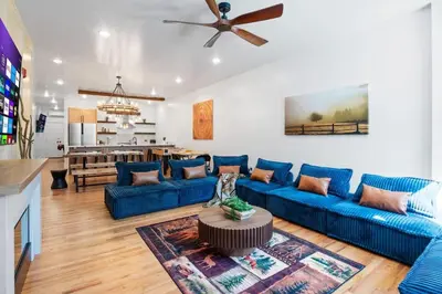 a living room with blue couches and a kitchen at The Grand Pocono Getaway Waterparks & Raceway in Pocono Summit