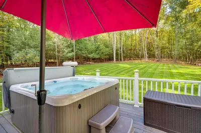 a hot tub on a deck with an umbrella at Hot Tub and Game Room Retreat Near Camelback in Reeders