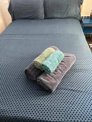 a pile of towels sitting on a bed at Cozy guest room 20mins to city in North Bergen