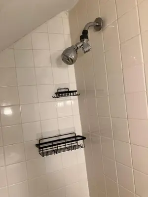 a white tiled shower with two shelves and a light at Quite and Sweet guest room near nyc in Guttenberg