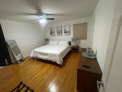 a bedroom with a white bed and a wooden floor at Modern Glam Getaway 30 minutes from NYC in West Orange