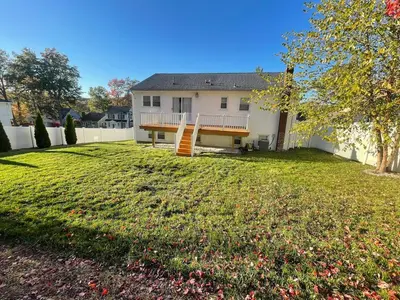a white house with a fence and a yard at Modern Glam Getaway 30 minutes from NYC in West Orange