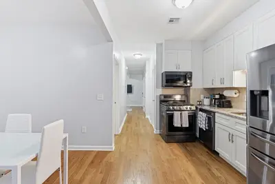 a kitchen with white cabinets and a table and a stove at Cozy 2BR Apartment in Jersey City with Smart Lock in Croxton