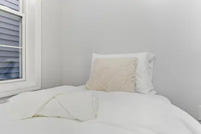 a white bed with a pillow and a window at Cozy 2BR Apartment in Jersey City with Smart Lock in Croxton