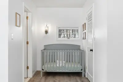a crib in a room with white walls and a window at The Waters Edge Escape in East Stroudsburg