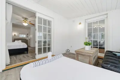 a white bedroom with a bed and a living room at The Waters Edge Escape in East Stroudsburg